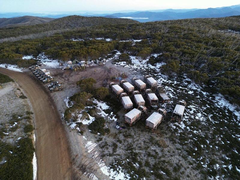 Army soldiers and vehicles camp in snow covered country.