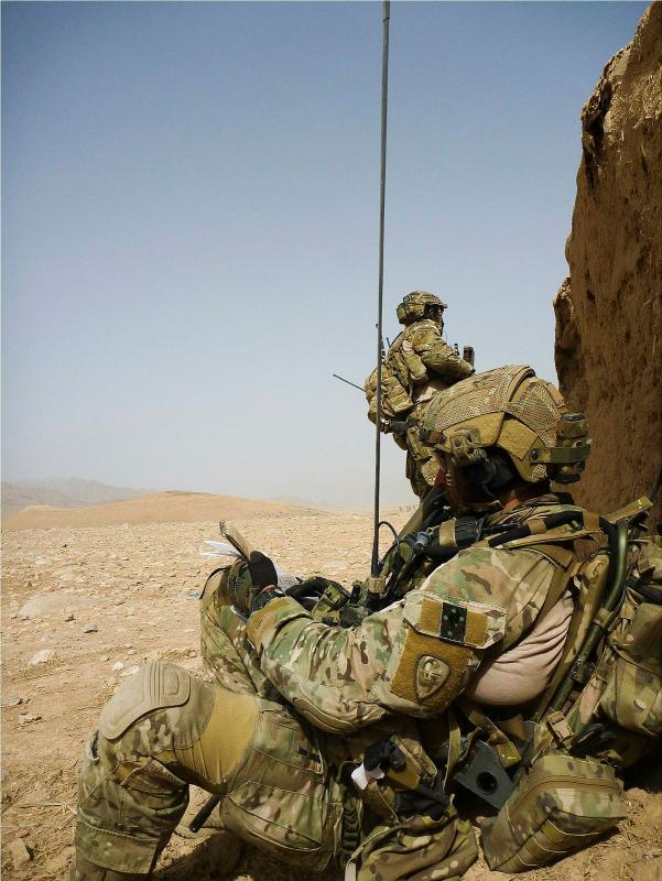 Two soldiers take cover behind in the desert.