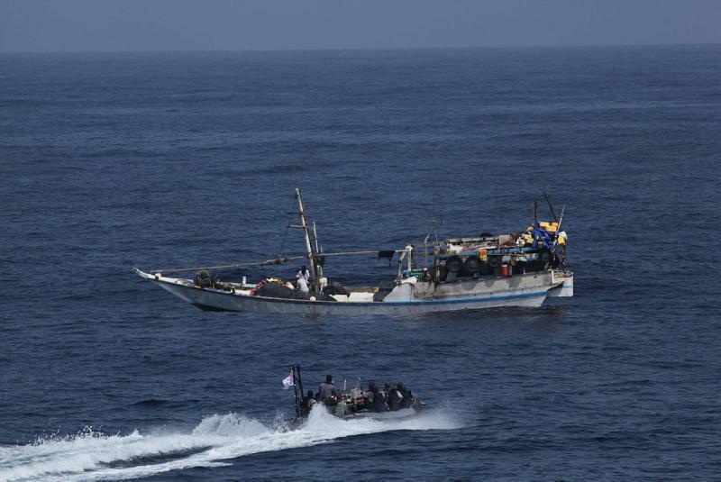 A small boat approaches a larger boat at sea.
