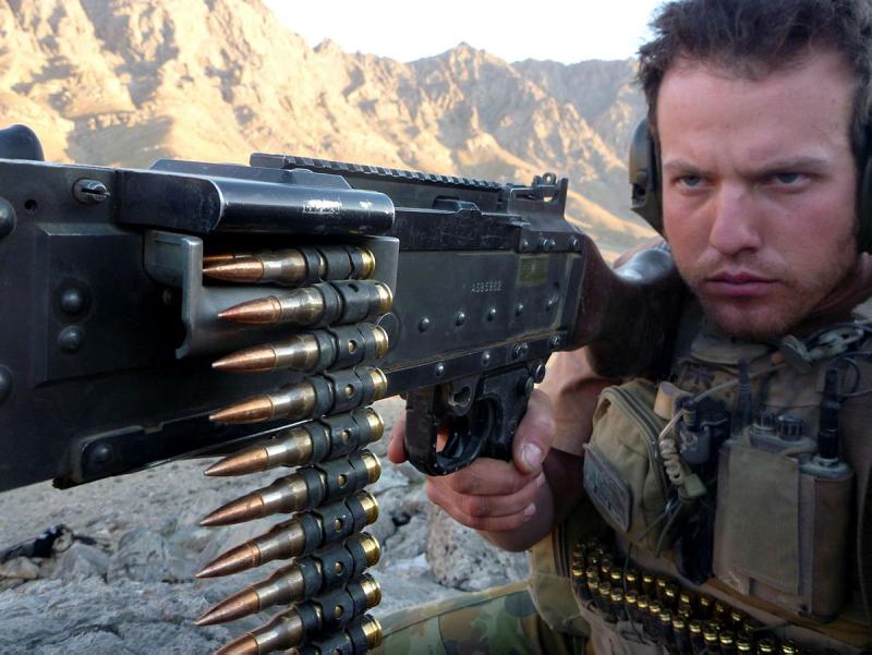 A military man takes aim with a large gun.