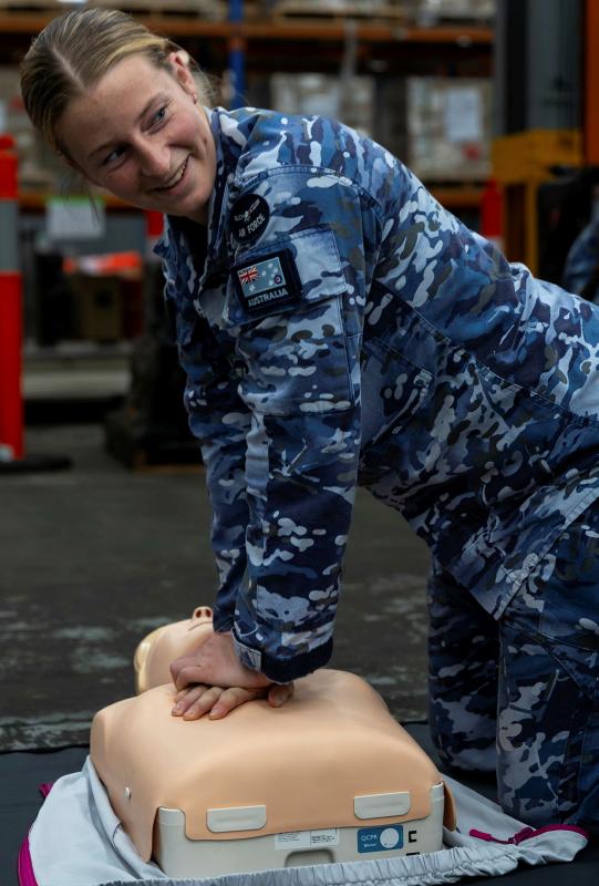 A female military person performs CPR on a dummy casualty.
