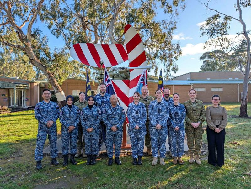 Royal Australian Air Force and Royal Malaysian Air Force traffic controllers stand smiling and face the camera.