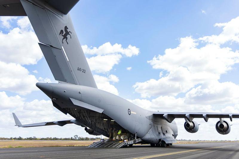 Military personnel work in the tail end of an aircraft.