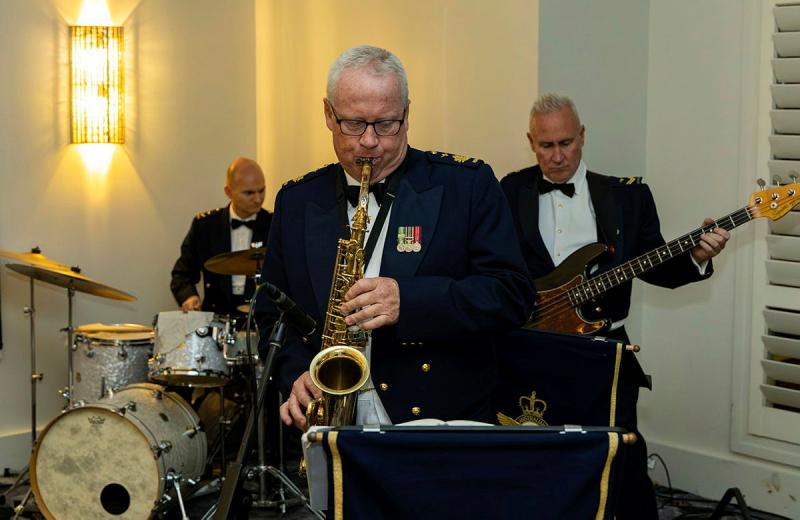 Three older men play either the drums, a guitar or a trumpet as a band.