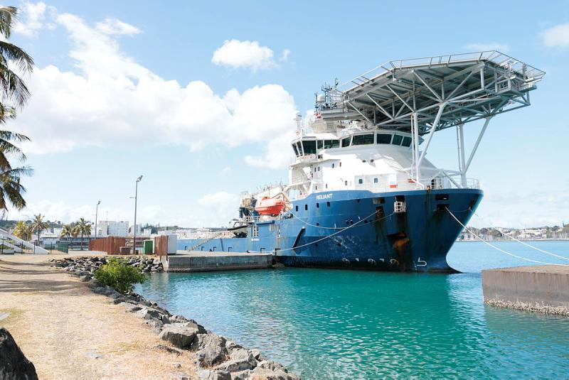 A Navy vessel is seen stationery in the water next to land.