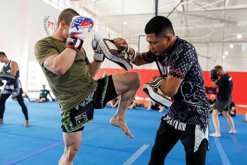 Two men spar with gloves on throwing punches and lifting knees.