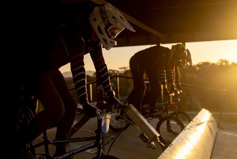Cyclists in helmets at sunset encounter a barrier on the road