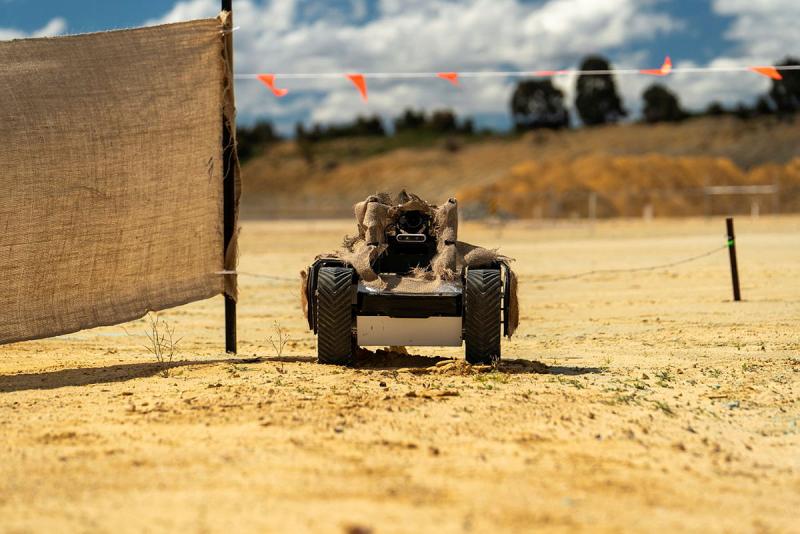 An uncrewed ground vehicle drives along a dirt road.