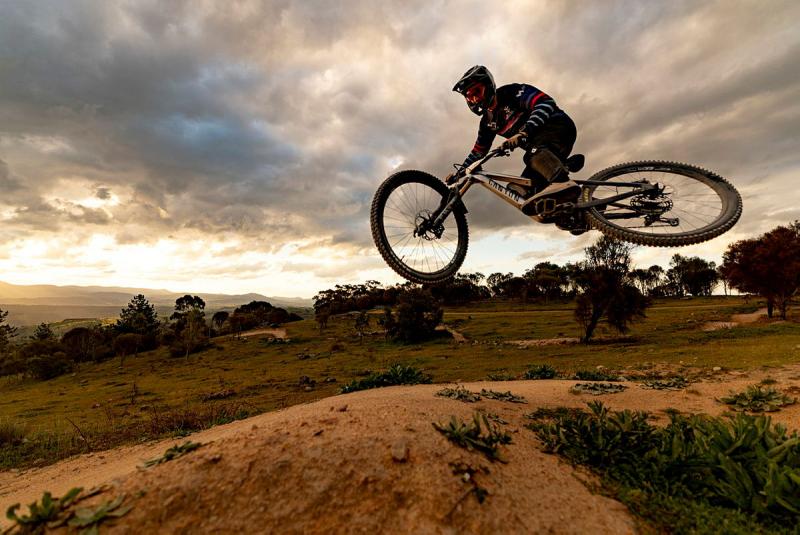 Cyclist hovers mid-air above the sandy and grassy ground
