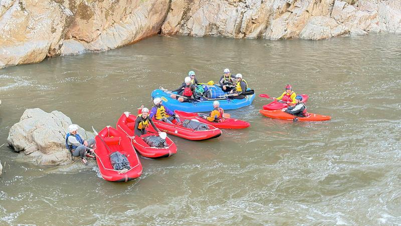 A small group of people in red and blue rafts float in close proximity to each other.
