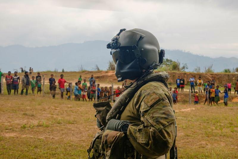 A pilot looks towards a crowd of civilians outside.