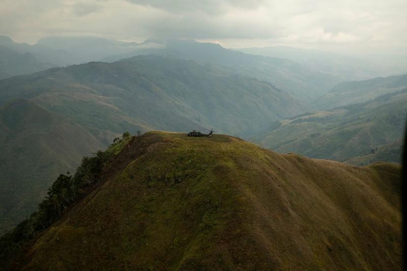 A helicopter parked at the peak of a mountaintop.