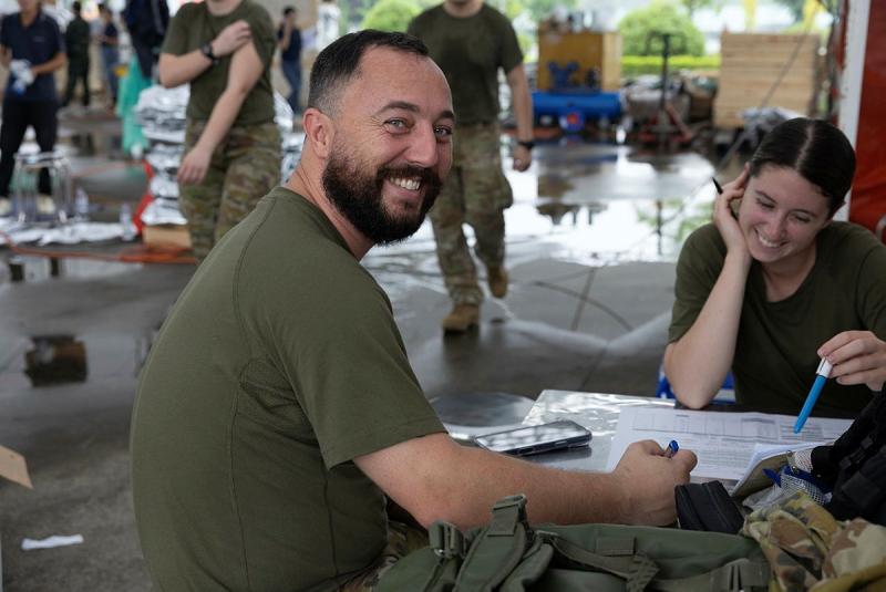 A RAAF Sergeant smiles at the camera as he and a colleague plan the provisions load for the trip to South Sudan.