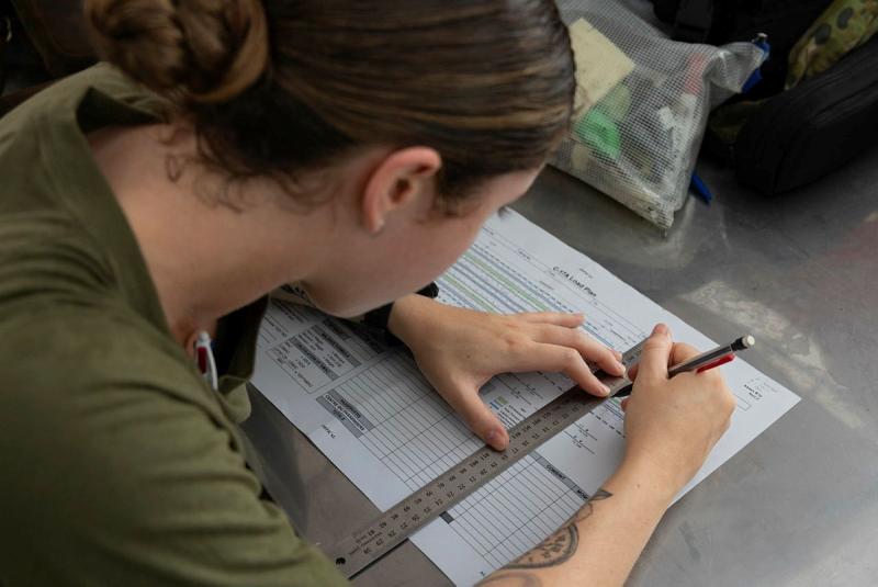 A woman uses a ruler to write on paper.