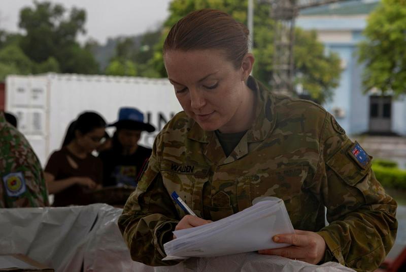 A woman in uniform writes on papers.