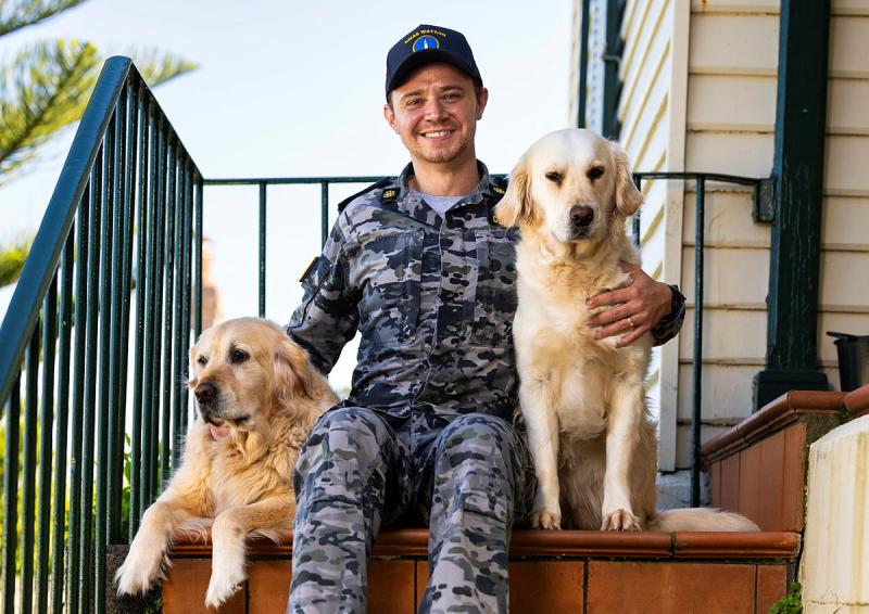 A man hugs two dogs. 