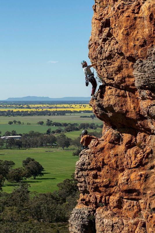 A person rock climbs a cliff face during the day.