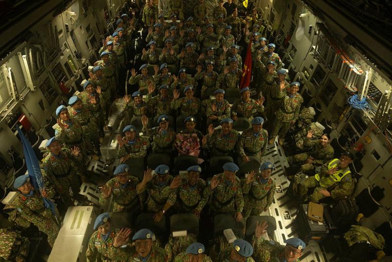 A large group of military personnel wave up from the cabin of an aircraft.