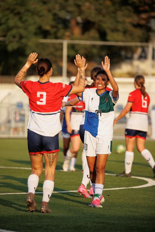 Opposing players in a soccer game double high five each other.