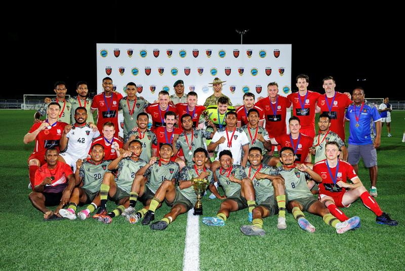 Two teams of soccer players group together for a photo with their medals.