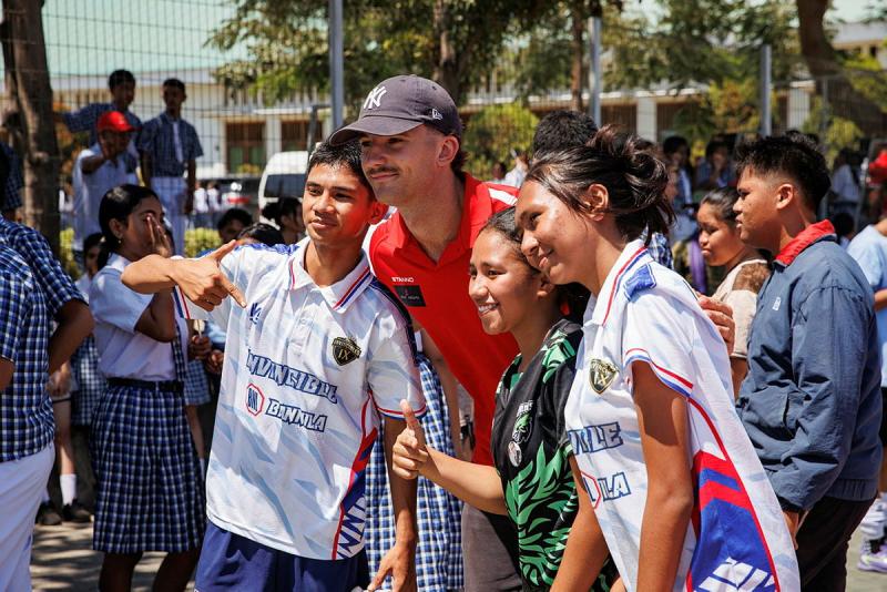 Students take a photo with an young adult man in red.