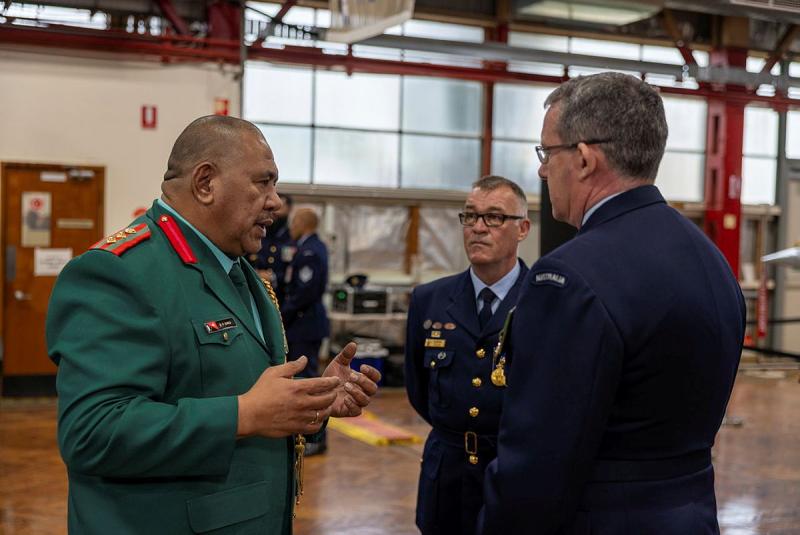 Three military men engage in a discussion.