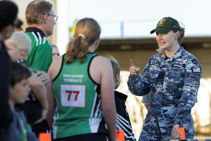 A military woman speaks to a group of civilian youth athletes and their famillies.