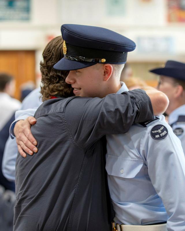 A woman hugs a young man in military uniform.