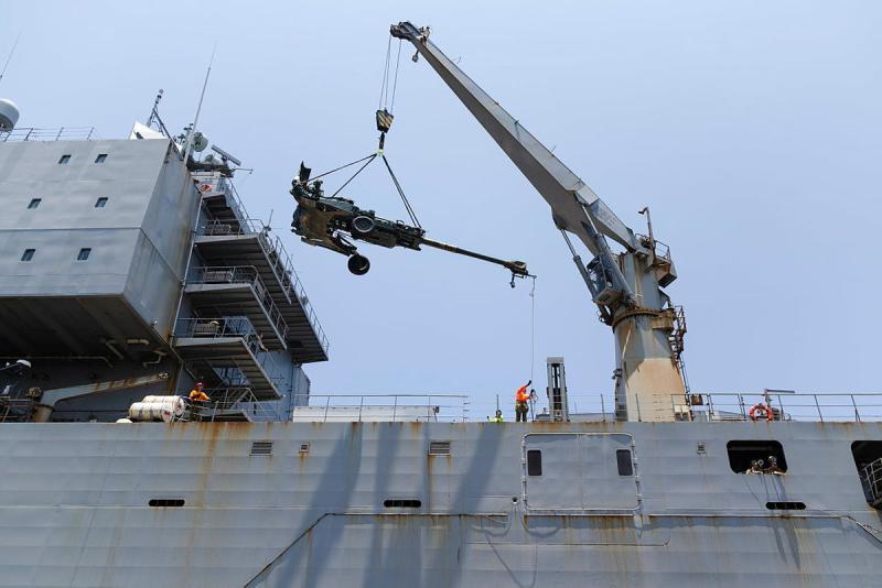 A large gun is craned onto a ship.