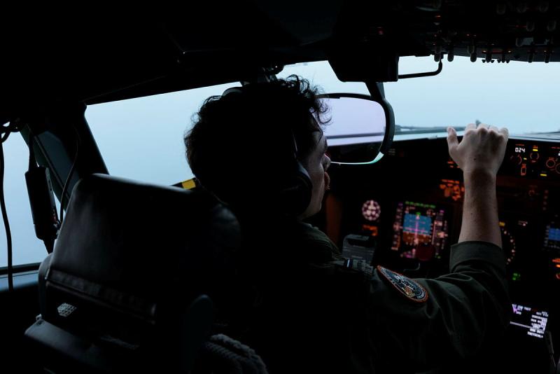 A pilot looks out the windscreen of an aircraft at a foggy sky.