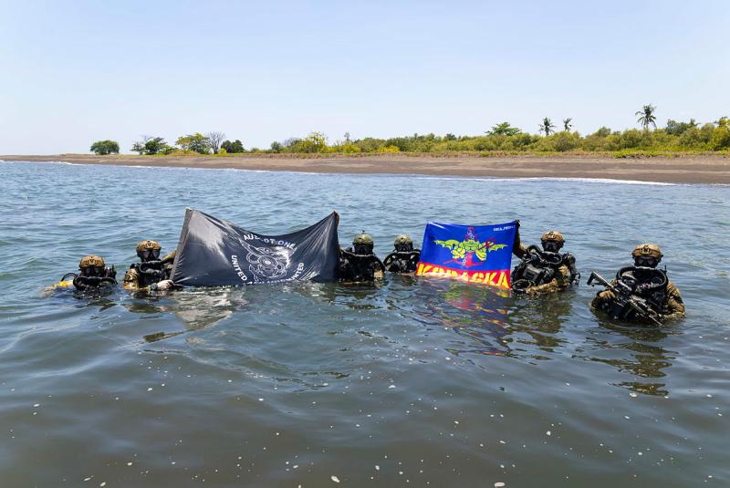 Divers in the ocean water holding up flags.