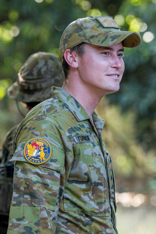 A man standing wearing an Army uniform and cap.