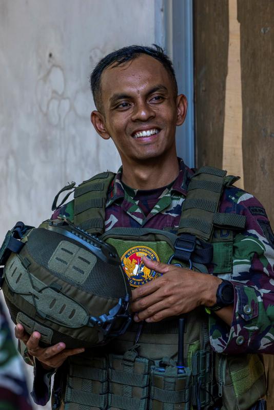 A man standing in Indonesian military uniform, holding his helmet.