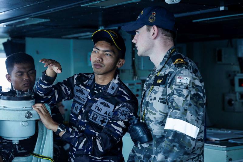 Two Navy members talk while on board a ship. 