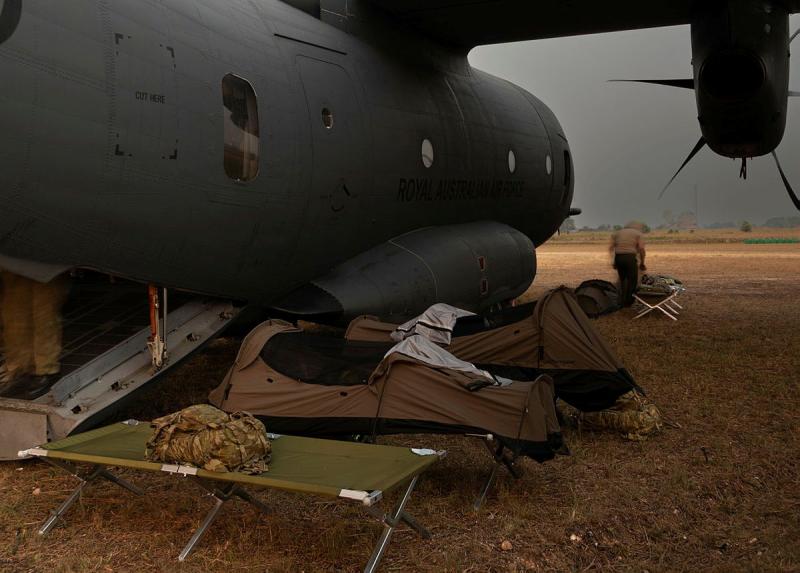 Swags and stretchers set up next to an aircraft in a field.