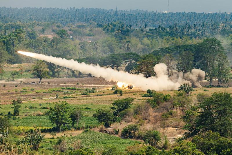 A missile shooting through the air leaving a plume of smoke behind it.