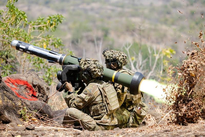 Two soldiers sitting on the ground shooting a missile launcher.