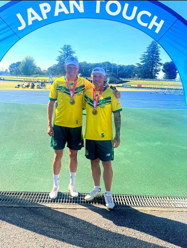 Two men in Australiana sports uniform and wearing medals stand under a banner reading 'Japan Touch'.