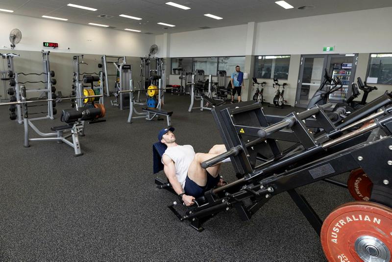A man uses the leg press machine in a gym.