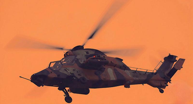 A helicopter flies in an orange sky.