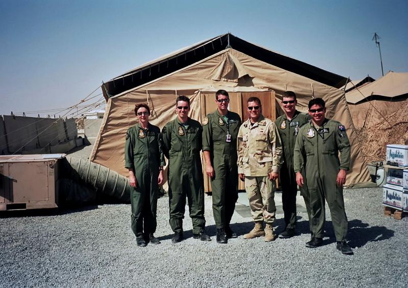 Group of men in military uniform in front of a beige tent