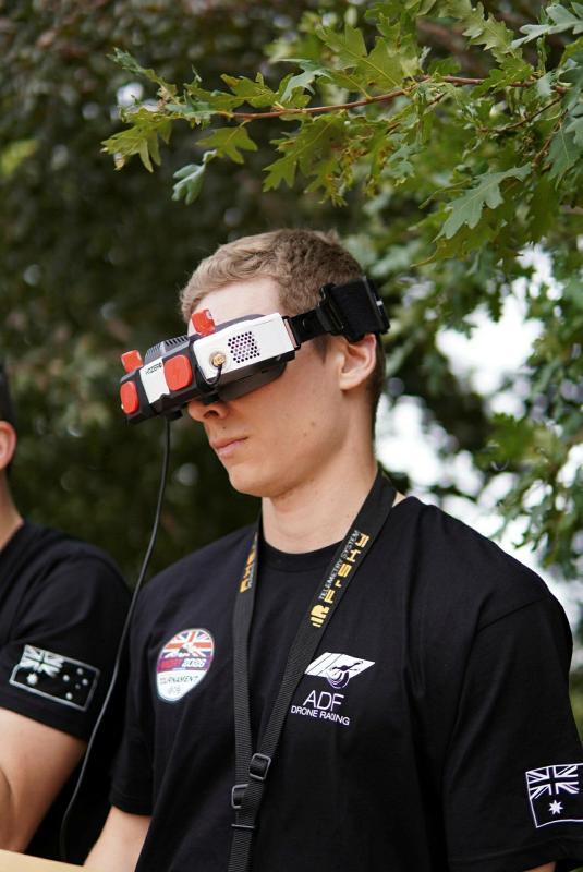 A man wearing high tech goggles and shirt from ADF drone racing.