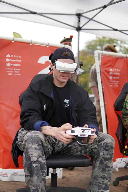 A seated man wearing high tech goggles and holding a controller.