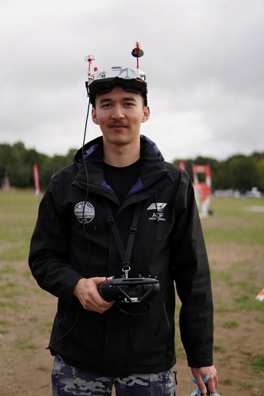 A man wearing high tech goggles and holds a controller while outside.