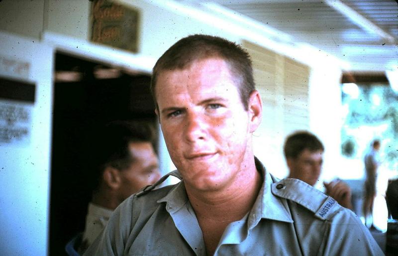 Man visible from shoulders up with three other men blurry behind him in the middle ground and background