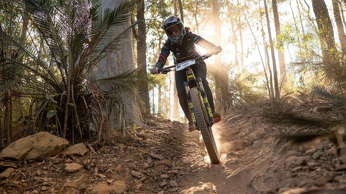 A cyclist rides downhill on a trail.