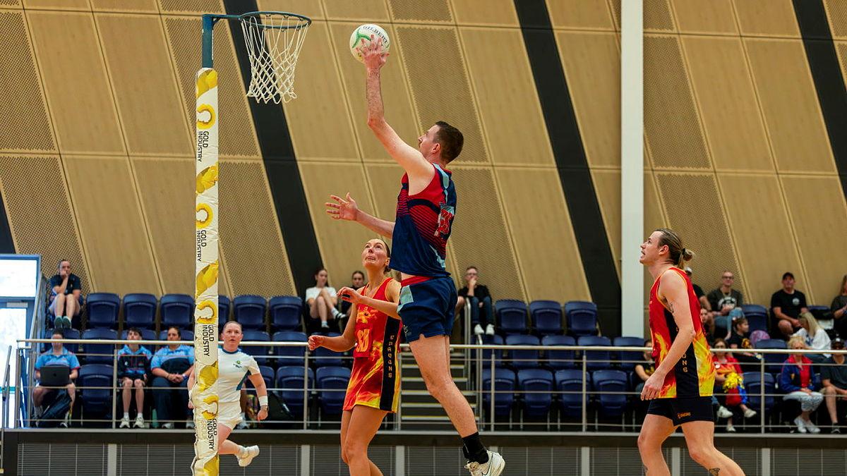 A man jumps to shot during a netball game.