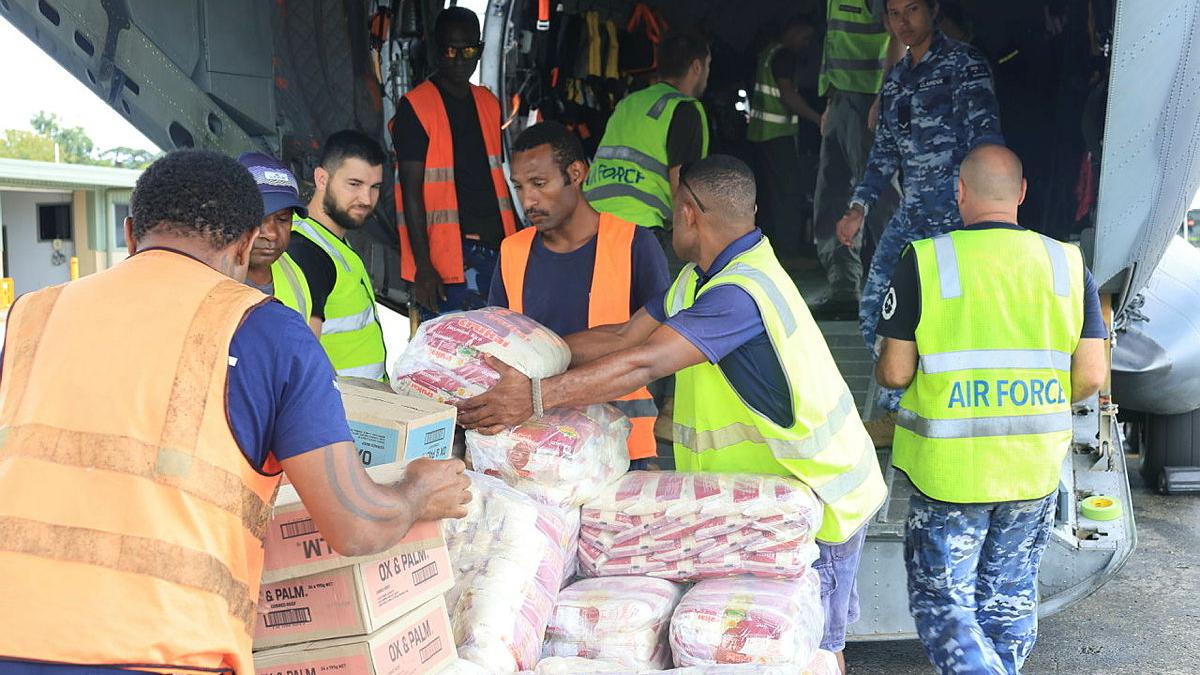 People in high-vis vests load supplies into the hull of an aircraft.