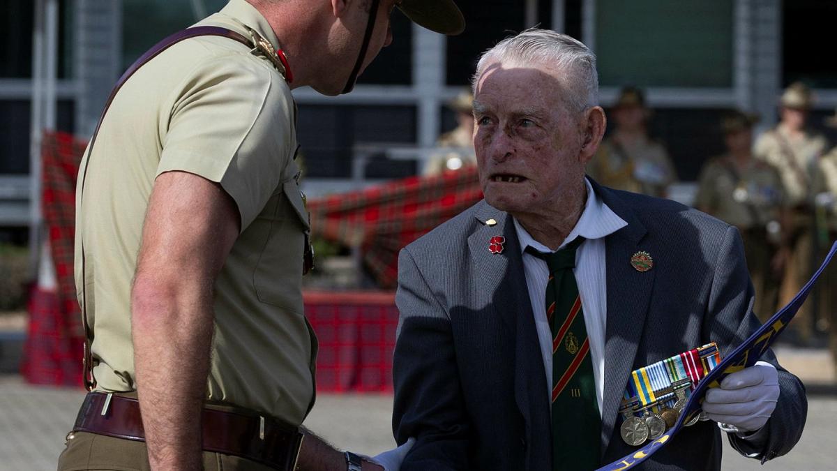 A soldier and an old man engage in discussion.