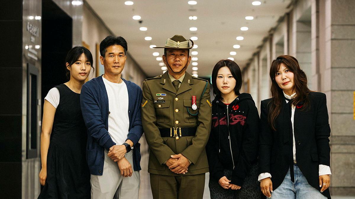A military man stands with four civilians.